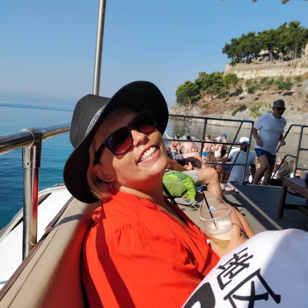 photo of smiling young woman on boat getting ready to sail from the port of Parga heading for Paxoi island in Western Greece