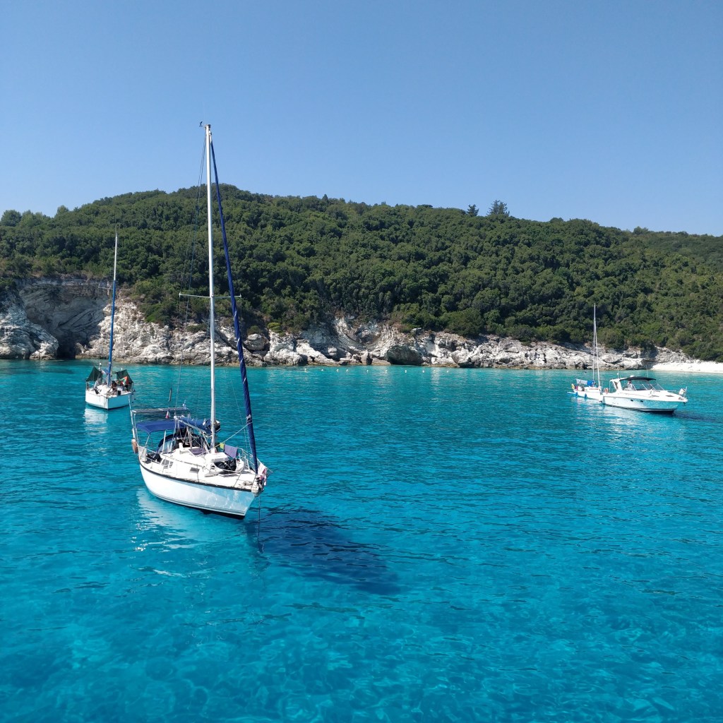Voutoumi beach on the island of Antipaxoi in the Ionian sea in Western Greece - photo of bright blue waters and white boats